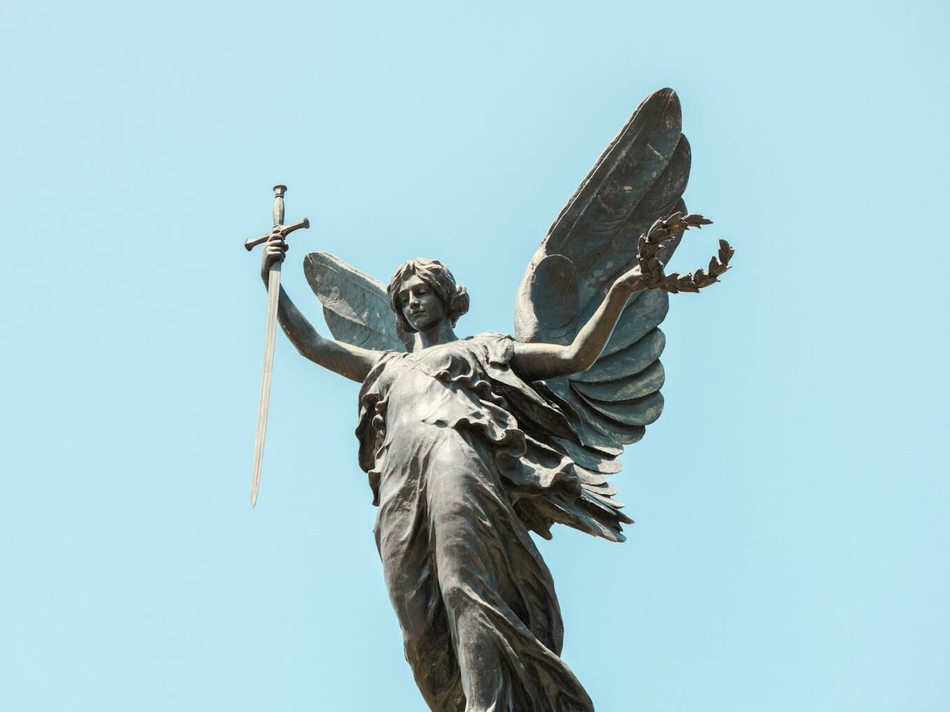 Photo by Benjamin Cheng a statue of an angel holding a sword
